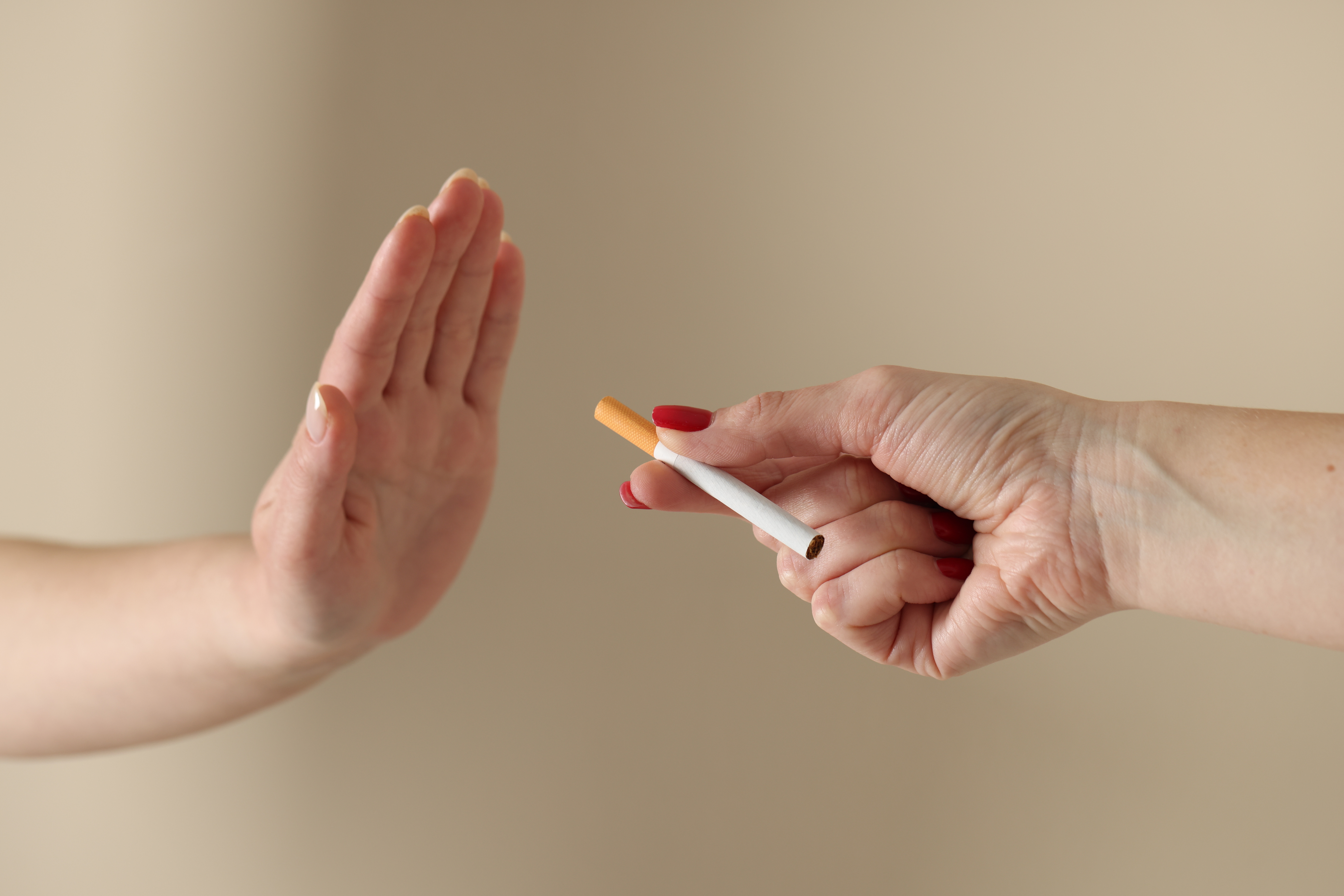 Woman refusing cigarette on blurred background, closeup